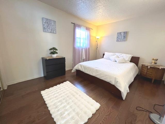 bedroom with baseboards, wood finished floors, and a textured ceiling
