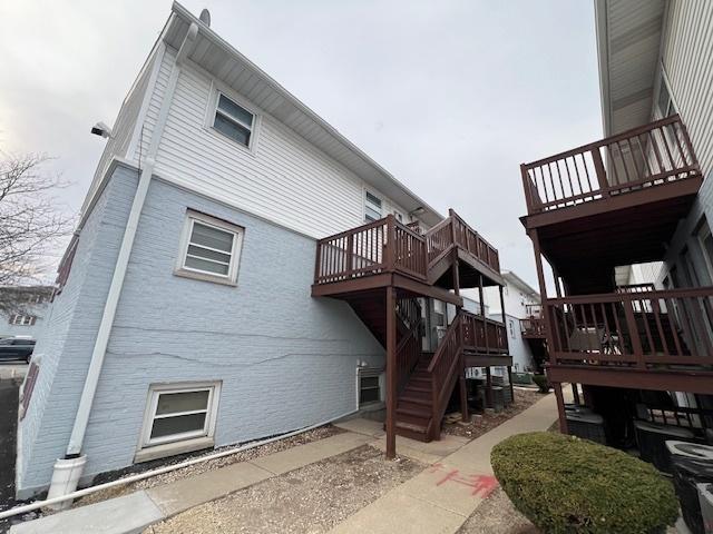 rear view of property with stairway and a deck