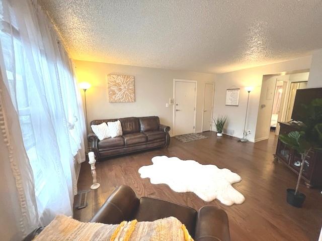living area with a textured ceiling, baseboards, and wood finished floors