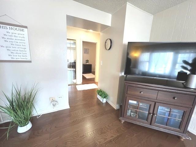 hallway featuring baseboards, wood finished floors, and a textured ceiling
