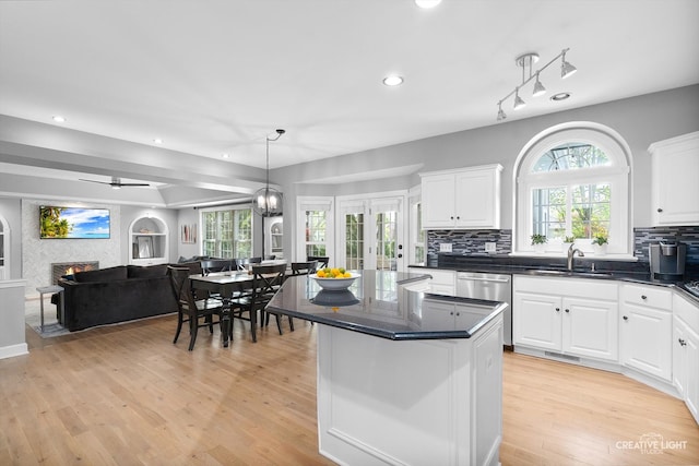 kitchen with dishwasher, a sink, white cabinets, tasteful backsplash, and open floor plan