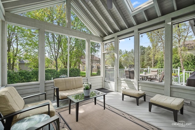 sunroom featuring a skylight, outdoor lounge area, and lofted ceiling