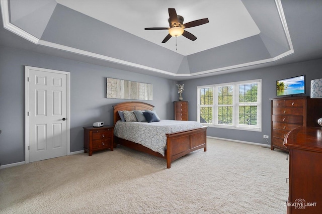 carpeted bedroom with a raised ceiling, baseboards, and ceiling fan