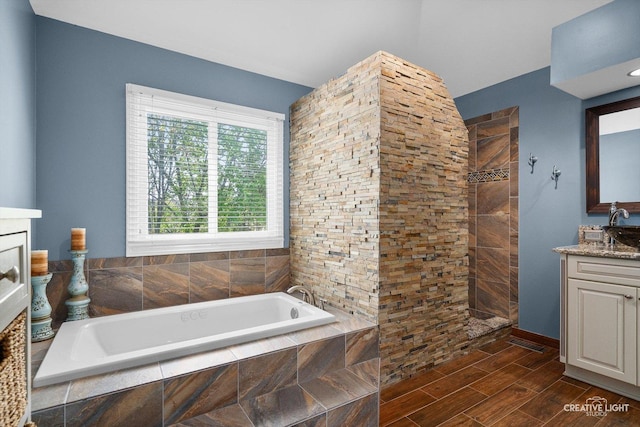 bathroom featuring vanity, a bath, walk in shower, and wood finished floors