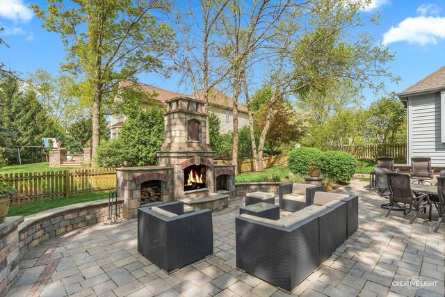 view of patio / terrace with an outdoor living space with a fireplace, a fenced backyard, and outdoor dining space