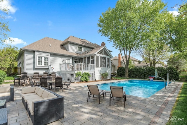 view of pool with a sunroom, outdoor lounge area, a patio, and fence