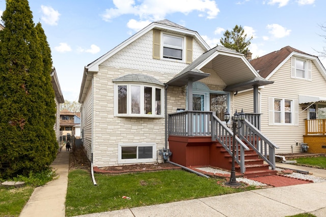 bungalow-style house with stone siding and a front lawn