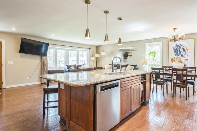 kitchen featuring open floor plan, dishwasher, a sink, and light wood-style floors