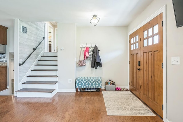 entryway featuring baseboards, wood finished floors, and stairway