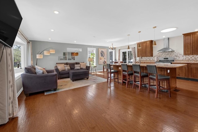 living room with recessed lighting, wood finished floors, and a wall unit AC