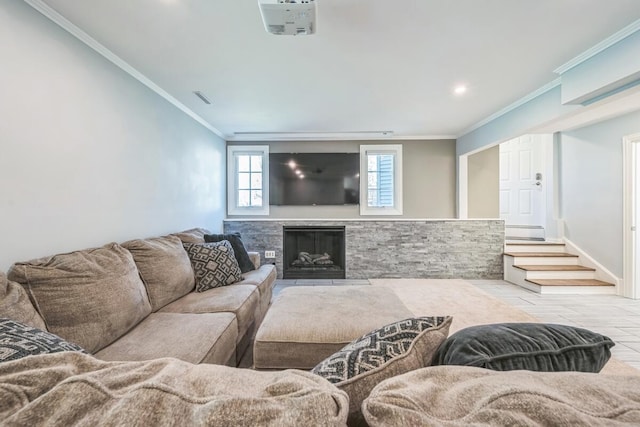 living room featuring baseboards, ornamental molding, a stone fireplace, and recessed lighting