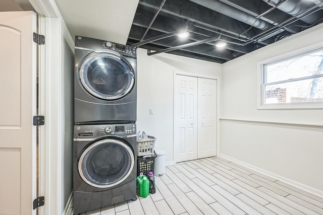 laundry room featuring baseboards, stacked washer / drying machine, and wood finished floors
