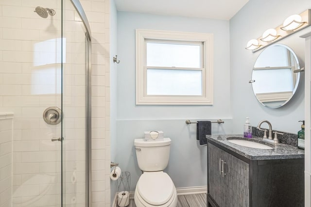 bathroom with toilet, vanity, and a tile shower