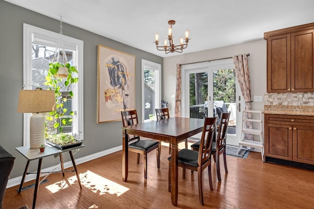 dining space with baseboards, wood finished floors, and a chandelier