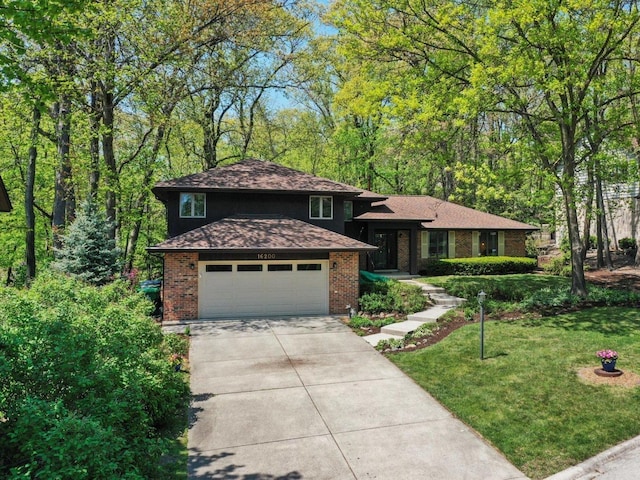 tri-level home featuring brick siding, a garage, concrete driveway, and a front lawn