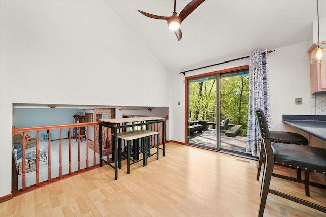 dining room featuring high vaulted ceiling, a ceiling fan, wood finished floors, and baseboards