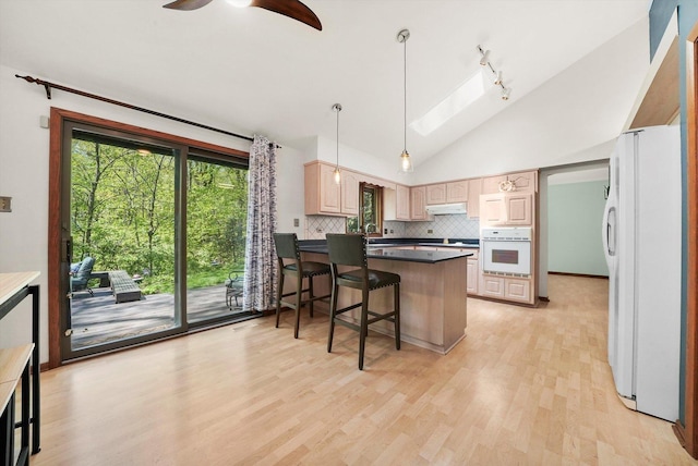 kitchen featuring white appliances, a peninsula, light wood-style flooring, light brown cabinets, and backsplash