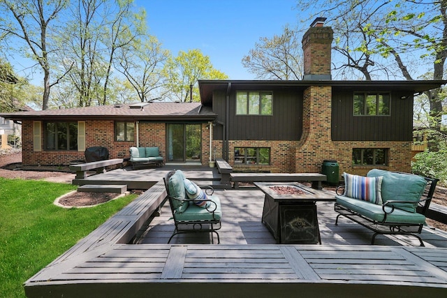 back of house featuring an outdoor living space with a fire pit, a deck, and a chimney