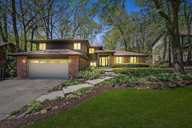 view of front of property featuring concrete driveway, a garage, brick siding, and a front yard