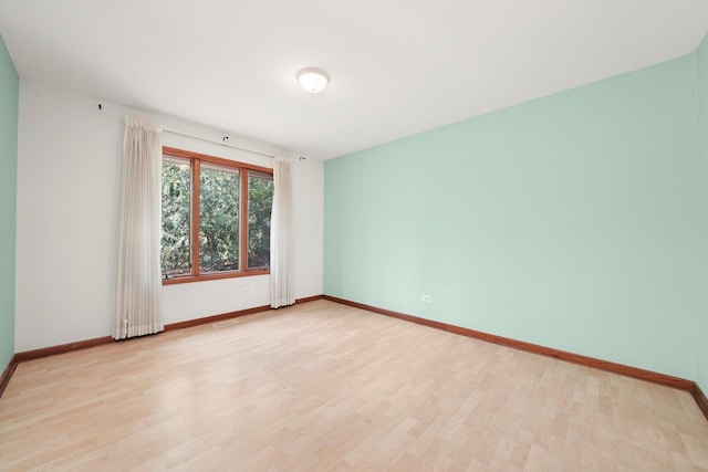 spare room featuring light wood finished floors and baseboards