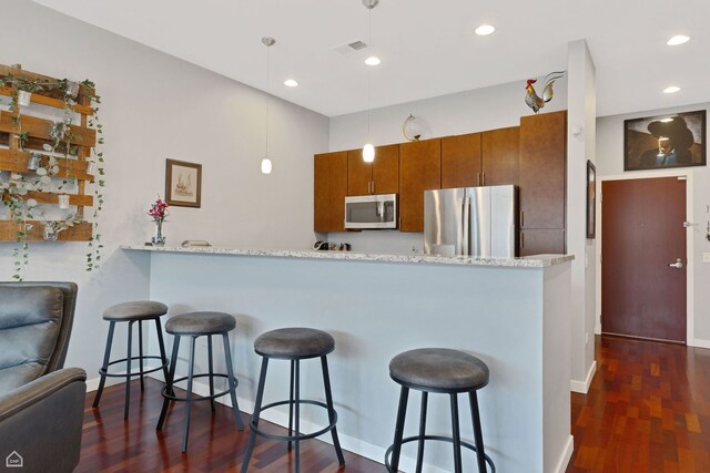 3920 N Sheridan Rd Unit 304, Chicago, IL 60613 - kitchen featuring a peninsula, dark wood-type flooring, a kitchen bar, brown cabinetry, and stainless steel appliances