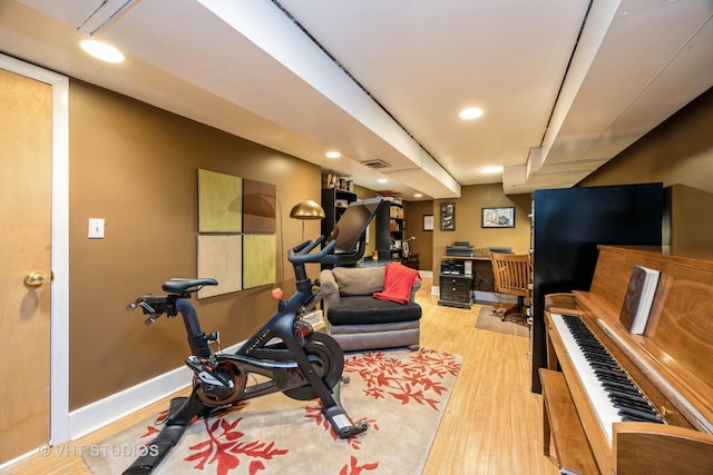 exercise area featuring baseboards, wood finished floors, and recessed lighting