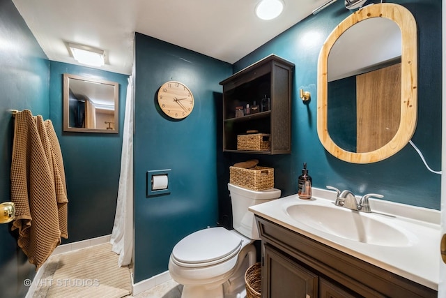 bathroom featuring tile patterned floors, baseboards, vanity, and toilet
