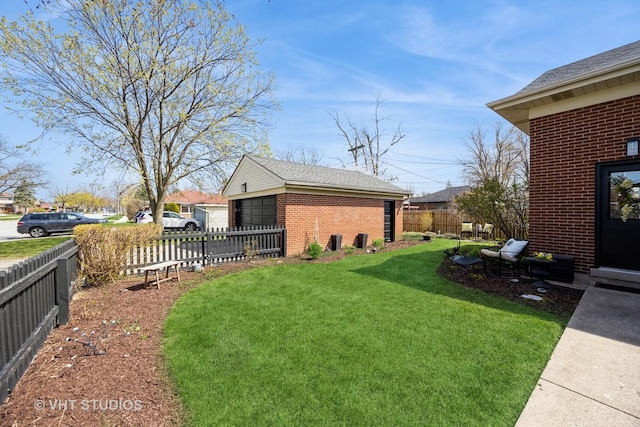 view of yard with a detached garage, an outbuilding, and fence