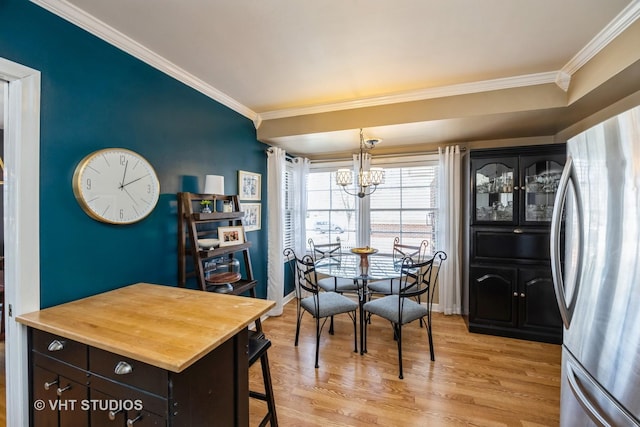 dining area with light wood-type flooring, baseboards, a notable chandelier, and ornamental molding