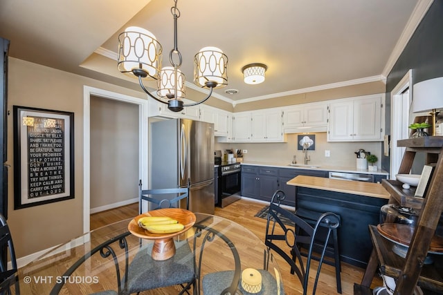 kitchen with stainless steel appliances, light countertops, white cabinetry, and crown molding