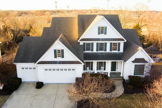 view of front of home with a standing seam roof, a porch, driveway, and metal roof