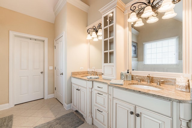 bathroom featuring an inviting chandelier, ornamental molding, a sink, tile patterned floors, and double vanity