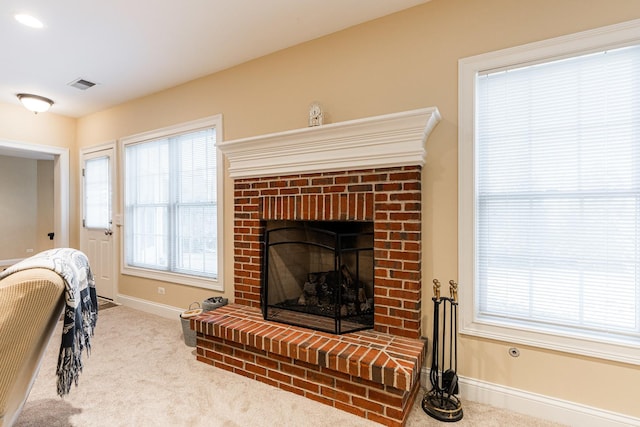 carpeted living room with visible vents, baseboards, a fireplace, and a healthy amount of sunlight