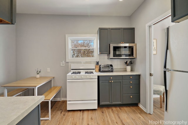 95 Hillside Ct, Fox Lake, IL 60020 - kitchen featuring a toaster, white appliances, light wood-style flooring, light countertops, and decorative backsplash