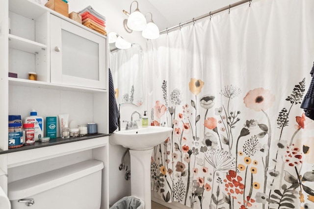 bathroom featuring curtained shower, a sink, and toilet
