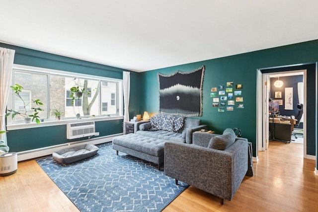 living room with an AC wall unit, a baseboard heating unit, and wood finished floors