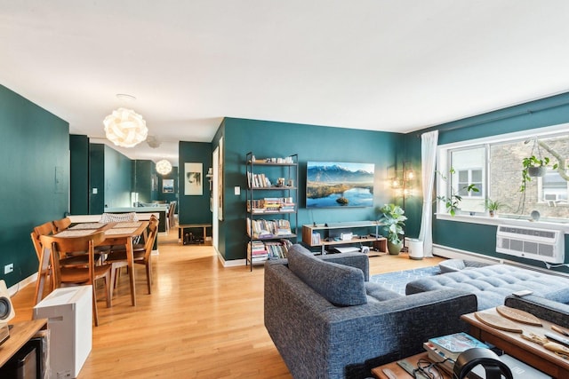 living area with baseboards, an inviting chandelier, a wall mounted AC, light wood-style floors, and a baseboard heating unit