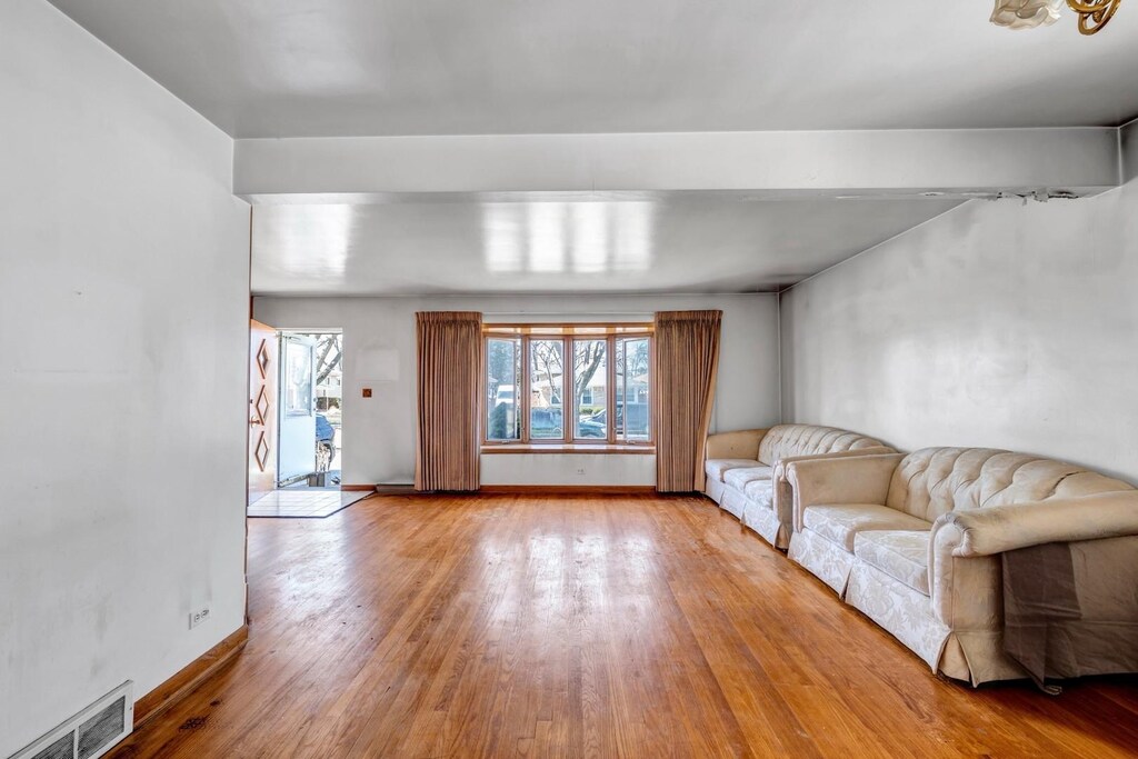unfurnished living room featuring baseboards, visible vents, and wood finished floors