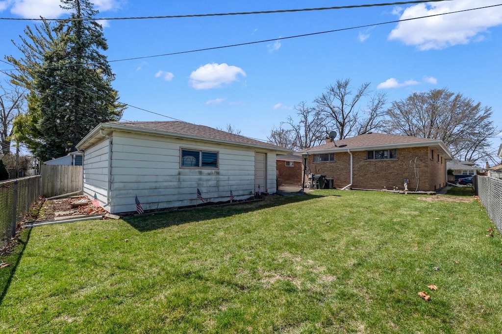 rear view of house featuring a fenced backyard and a lawn