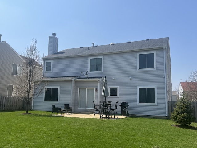 rear view of property with a yard, a patio area, a chimney, and fence