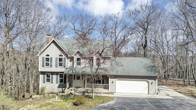 view of front of property featuring a garage, a porch, driveway, and a chimney