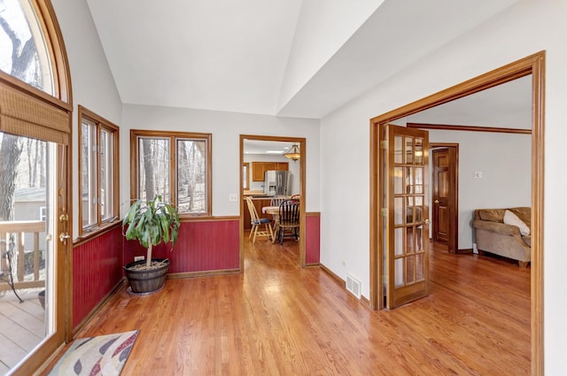 foyer with visible vents, baseboards, vaulted ceiling, and wood finished floors