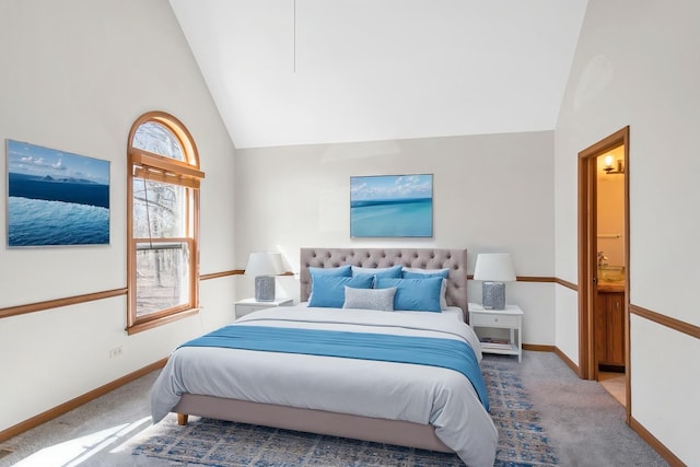 carpeted bedroom featuring high vaulted ceiling, baseboards, and connected bathroom
