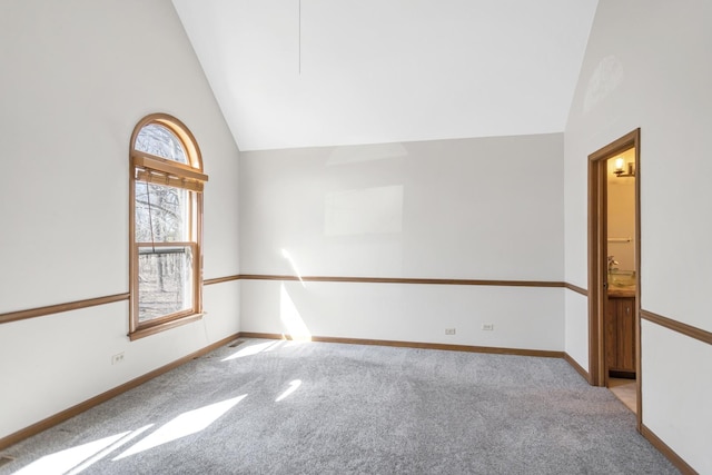 carpeted spare room with high vaulted ceiling and baseboards