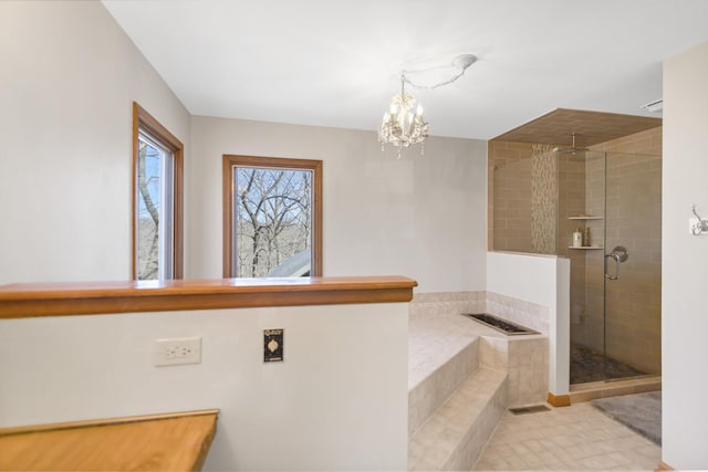 bathroom featuring tile patterned flooring, a shower stall, a chandelier, and a garden tub