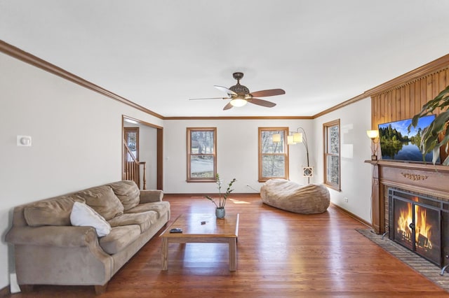 living area with a fireplace with flush hearth, wood finished floors, a ceiling fan, and ornamental molding