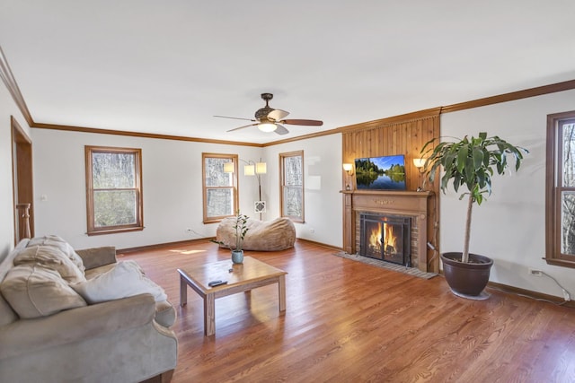 living area with wood finished floors, a ceiling fan, a brick fireplace, and a healthy amount of sunlight