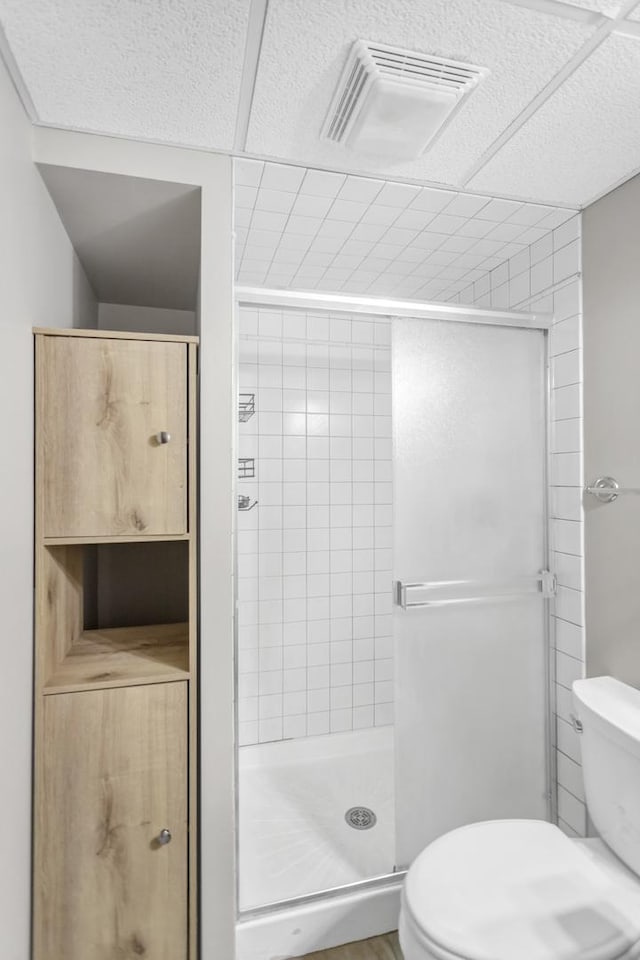 full bath with toilet, a stall shower, and visible vents