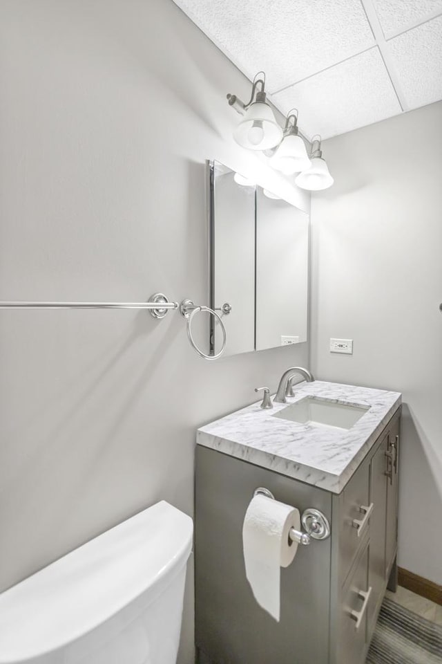 half bath featuring toilet, vanity, and baseboards