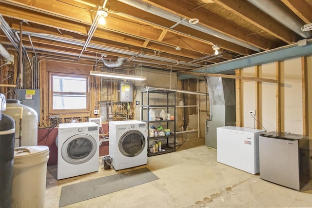 below grade area featuring washing machine and clothes dryer, heating unit, and fridge